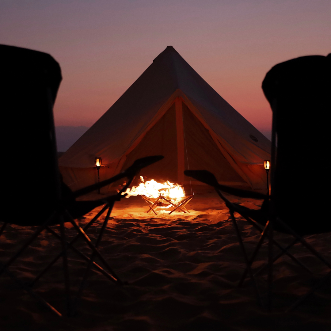 Campfire and camp chairs in front of the Bedouin bell tent at nightfall