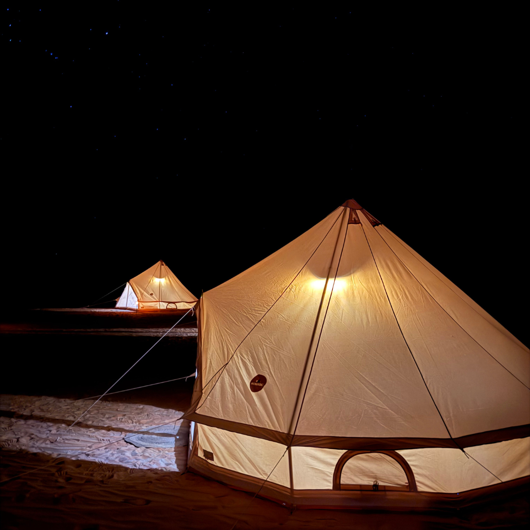 The Bedouin bell tent glowing at night with a second tent behind