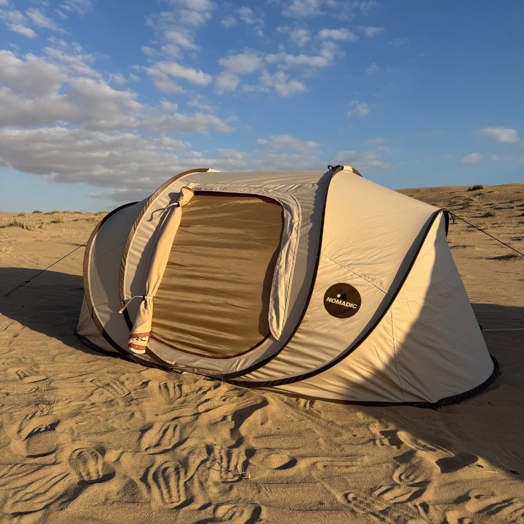 The Explorer pop-up tent open on pale sand, mattress visible inside