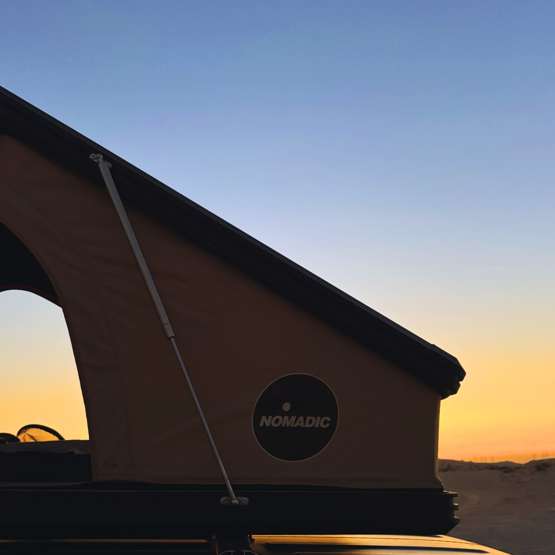The Nomad rooftop tent silhouetted at dusk with the Nomadic badge visible