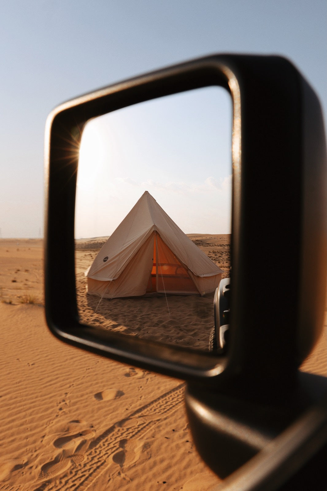 Glamping tent reflected in a car wing mirror in the desert