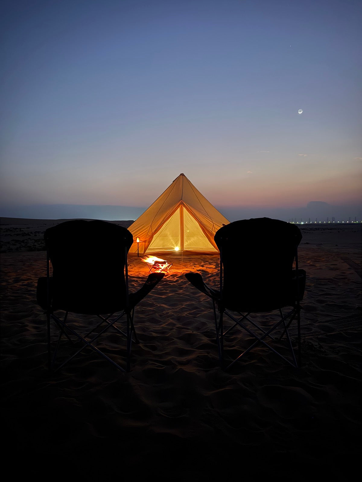 Camp chairs at dusk under a rising moon